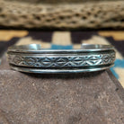 Ornate stamped sterling silver cuff by Diane Wylie, featuring intricate geometric hand-stamped patterns framed by polished silver borders in a handcrafted open cuff design.