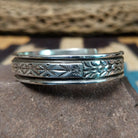 Ornate stamped sterling silver cuff by Diane Wylie, featuring intricate geometric hand-stamped patterns framed by polished silver borders in a handcrafted open cuff design.