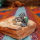 Ornate Turquoise Ring by Raymond Coriz with oval turquoise stone, fluted silverwork, and split band.
