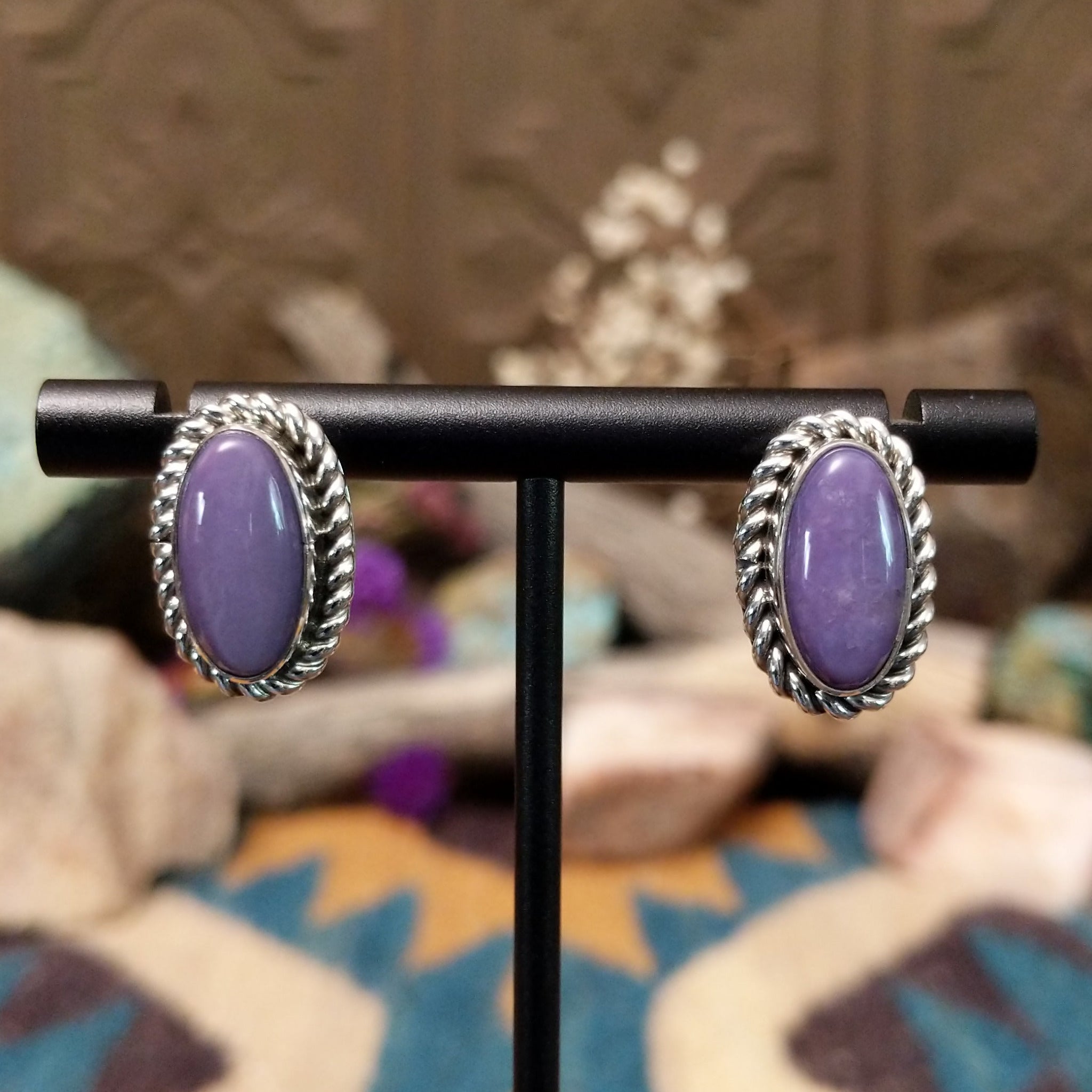 Handcrafted sterling silver post earrings by Priscilla Smith featuring oval charoite cabochons in polished bezel settings with traditional twisted rope border detailing.