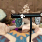Handcrafted sterling silver post earrings by Priscilla Smith featuring oval charoite cabochons in polished bezel settings with traditional twisted rope border detailing; artisan and Sterling Silver stamp.