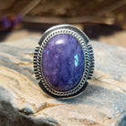 Sterling silver ring with large charoite stone set in an oval bezel, framed by twisted rope and stamped setting.