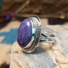 Sterling silver ring with large charoite stone set in an oval bezel, framed by twisted rope and stamped setting.