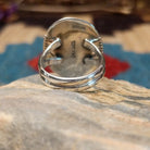 Sterling silver ring with large charoite stone set in an oval bezel, framed by twisted rope and stamped setting.