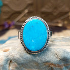 Sterling siler ring with turquoise set in the oval bezel, framed by twisted rope accents.