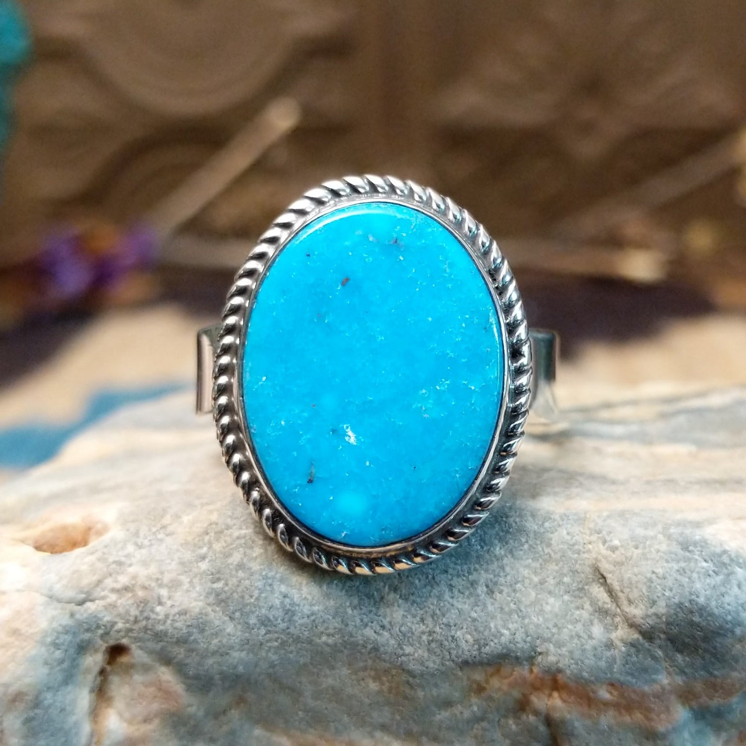 Sterling siler ring with turquoise set in the oval bezel, framed by twisted rope accents.