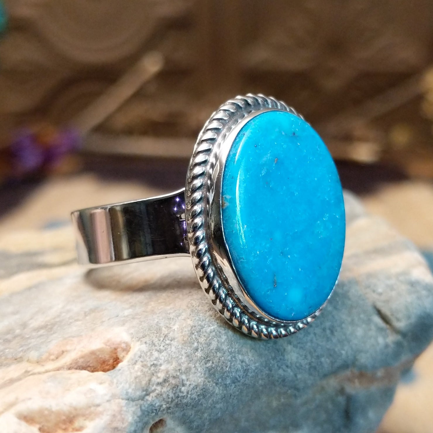 Sterling siler ring with turquoise set in the oval bezel, framed by twisted rope accents.