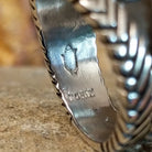 The artisan's signature is stamped on the underside of the band.