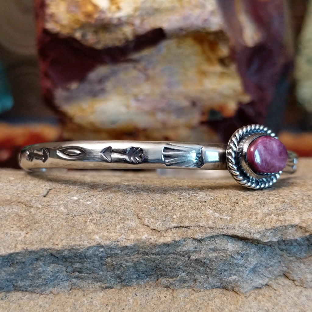 The cuff’s silver band showcases ornate detailing of arrows and other motifs.