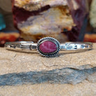 An oval purple spiny oyster shell cuff set in sterling silver with a twisted wire bezel.