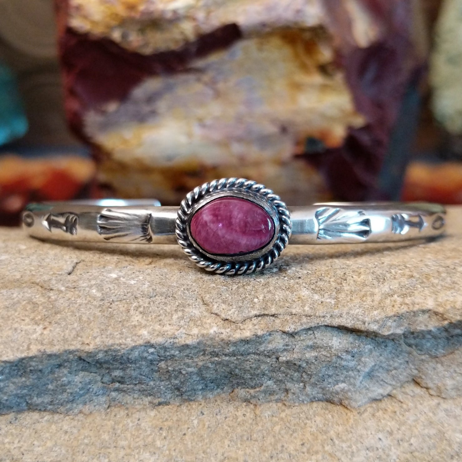 An oval purple spiny oyster shell cuff set in sterling silver with a twisted wire bezel.