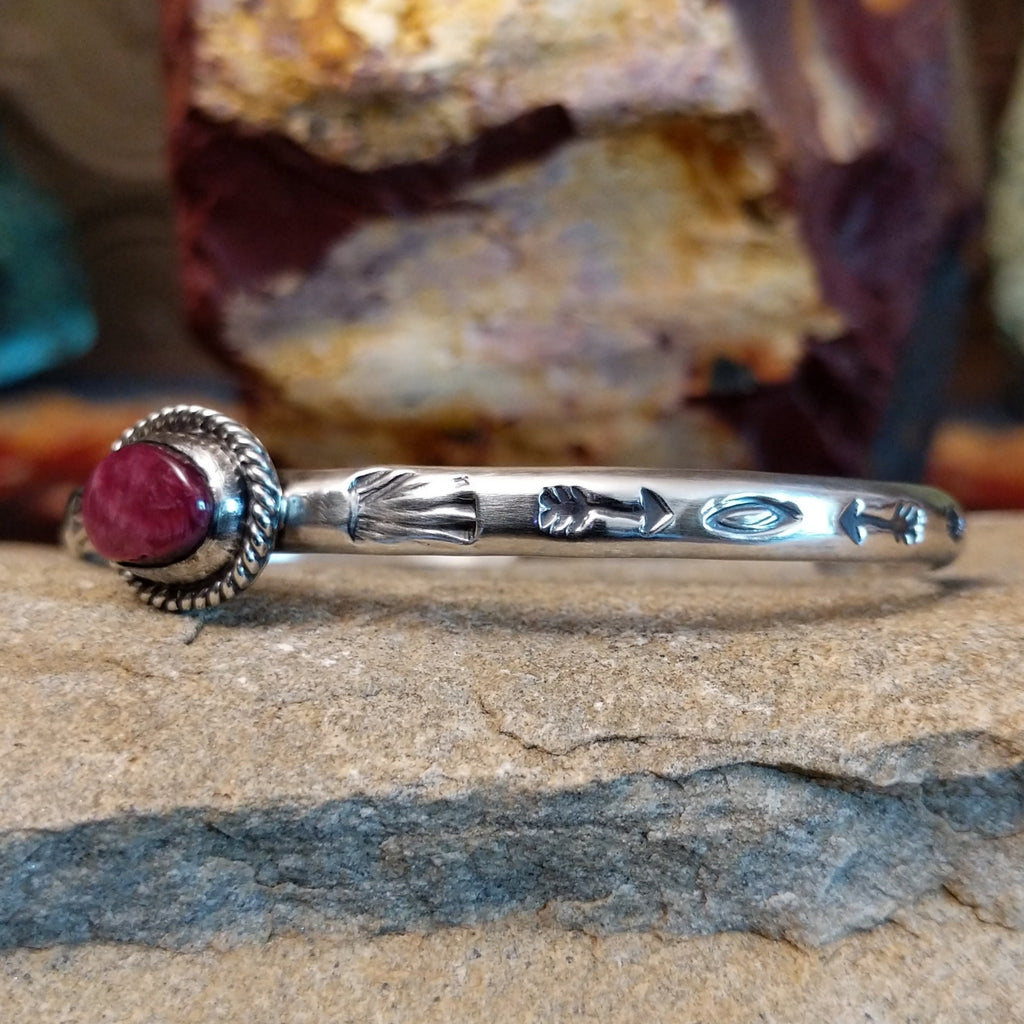 The cuff’s silver band showcases ornate detailing of arrows and other motifs.