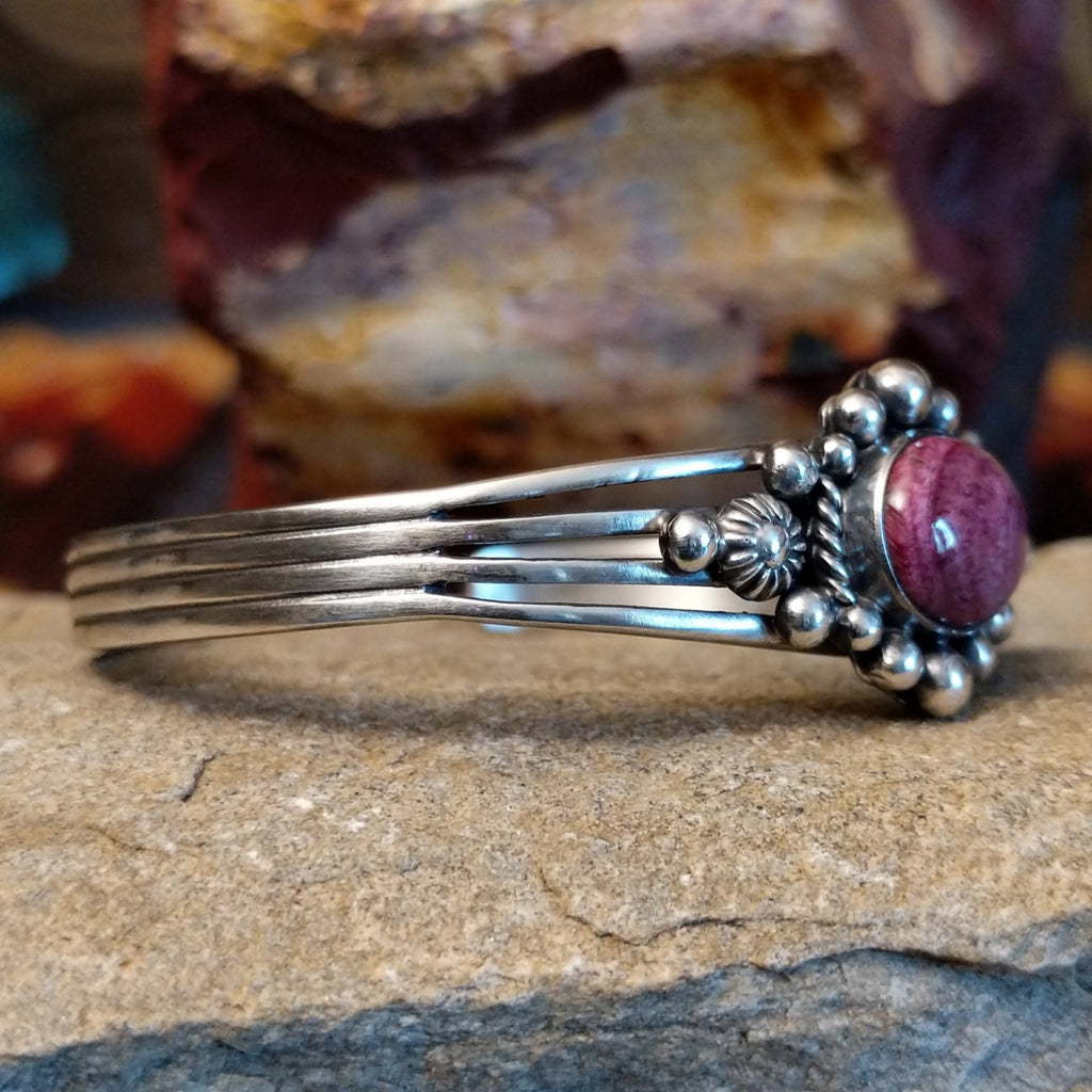 An oval purple spiny oyster shell cuff shines in sterling silver with ornate accents and polished band.