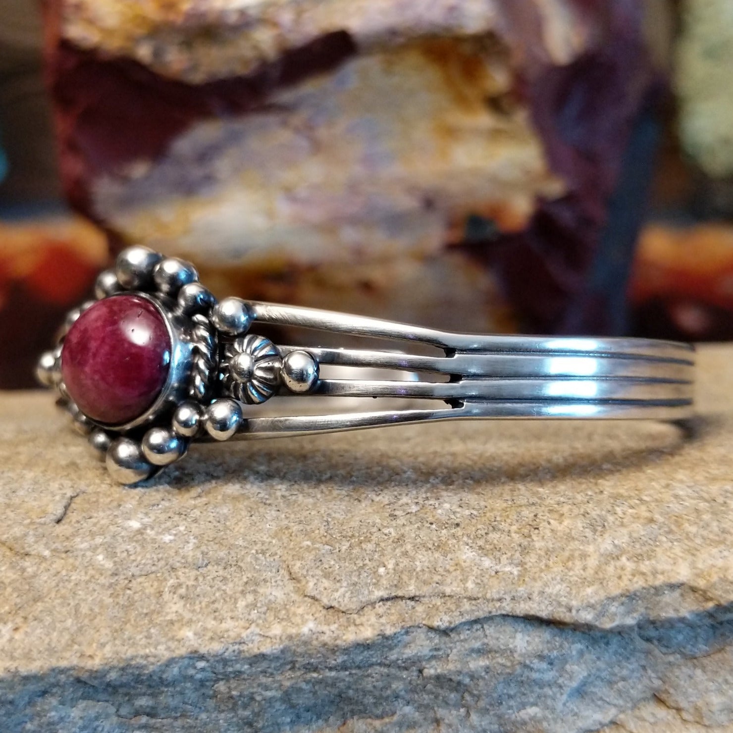 An oval purple spiny oyster shell cuff shines in sterling silver with ornate accents and polished band.