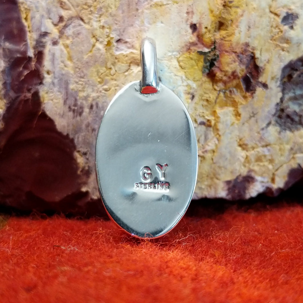 The artisan's initials are found on the back of the pendant.