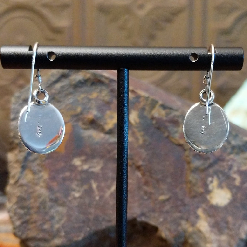 The back of the earrings feature the artisan's signature stamped on the back.
