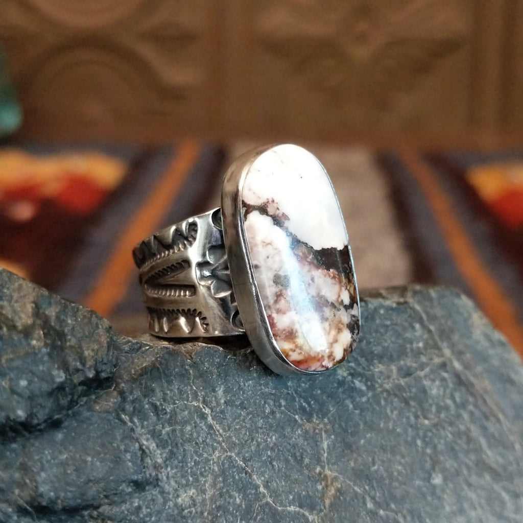 Side view showing the smooth bezel and ornate silver designs on the band.