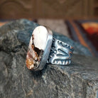Side view showing the smooth bezel and ornate silver designs on the band.