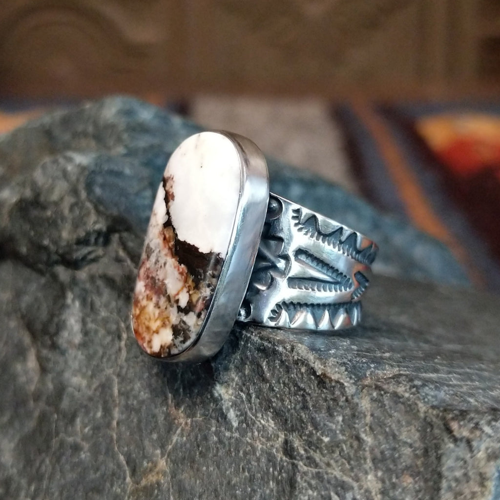 Side view showing the smooth bezel and ornate silver designs on the band.