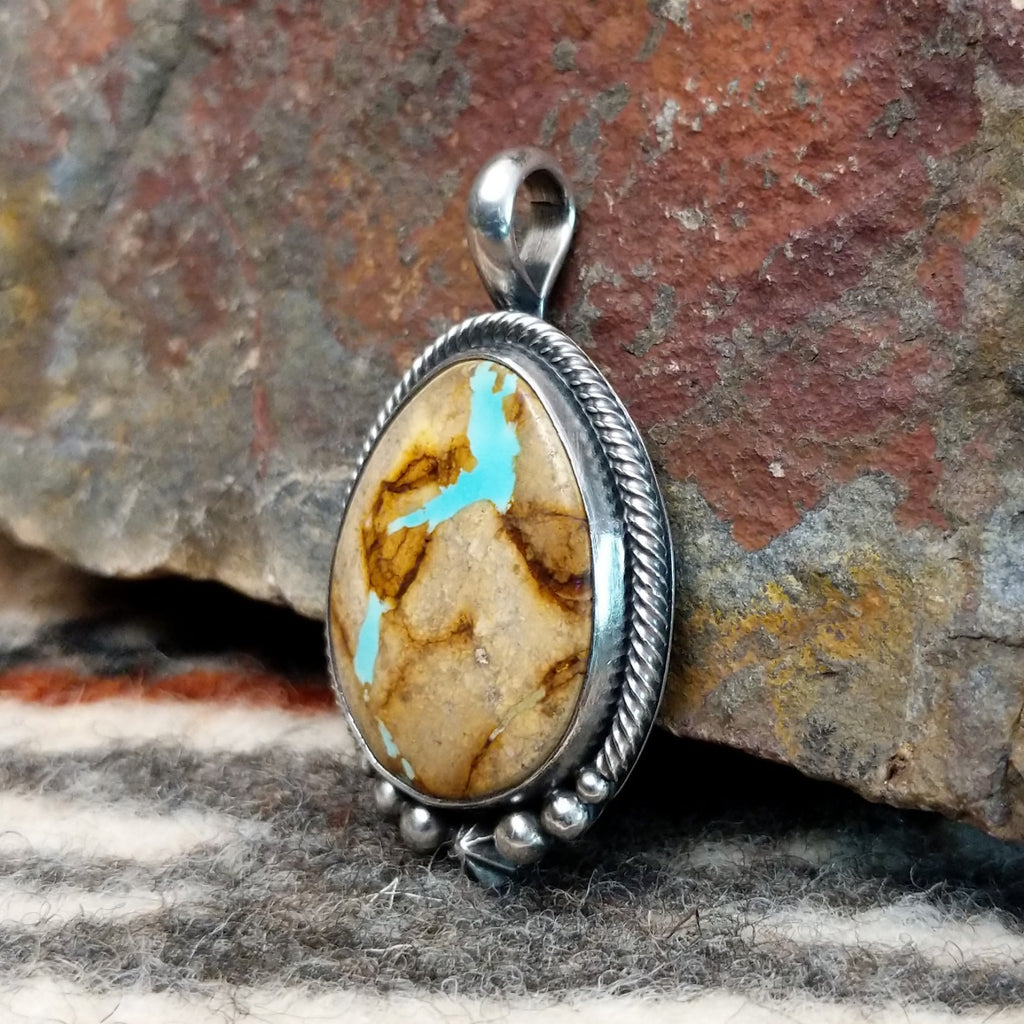 Sterling silver pendant with twisted rope and dotted accents, featuring boulder turquoise set in the bezel.