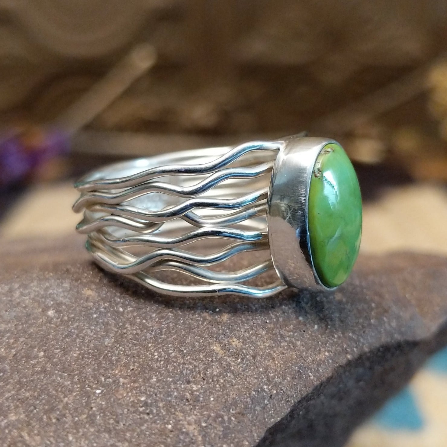 Sterling silver ring with Sonoran gold turquoise set in an oval bezel and strands of silver creating the band.