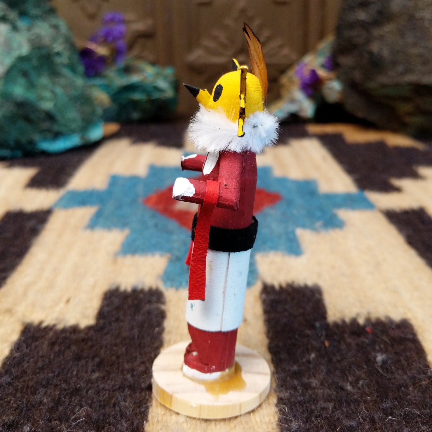Mini owl kachina by Rosalind Grey with yellow face, white fur collar, red body, and white geometric-patterned garment.