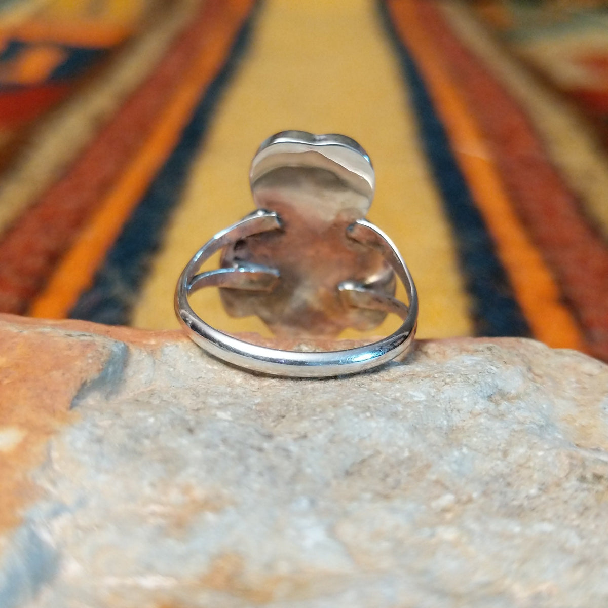 Rear view of an owl-shaped silver ring by Regina Kallestewa showing the smooth underside of the setting and polished split-shank band.