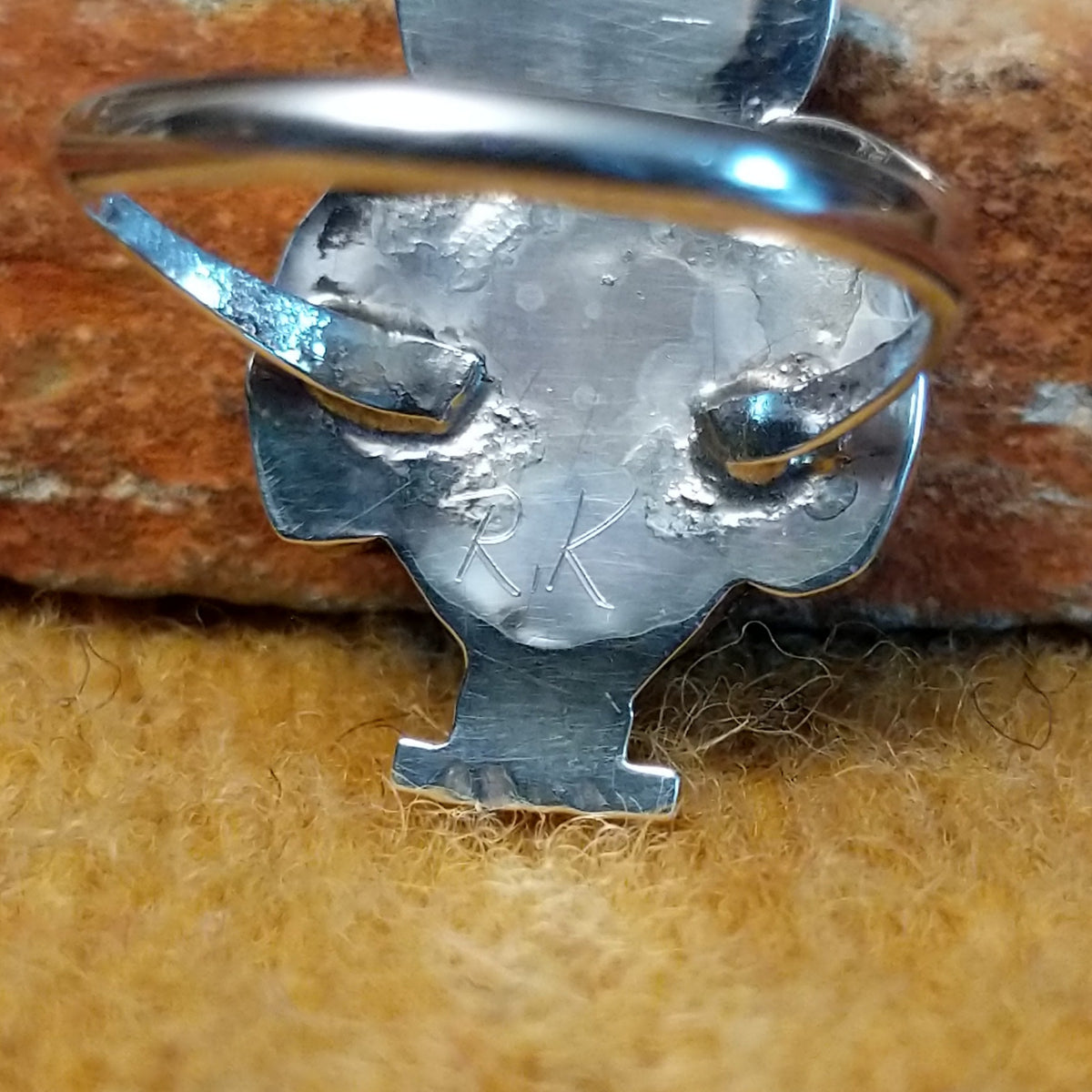 Rear view of an owl-shaped silver ring by Regina Kallestewa showing the smooth underside of the setting and polished split-shank band. Photo shows the artist's stamped signature. 