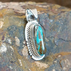 Handcrafted by Navajo artisan L.J., this capsule-shaped pendant features genuine #8 Turquoise set in sterling silver with a rope design accent.