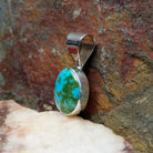 Sonoran Gold turquoise round pendant by Navajo artist Fred Guerro Jr., is handcrafted in sterling silver, side view.