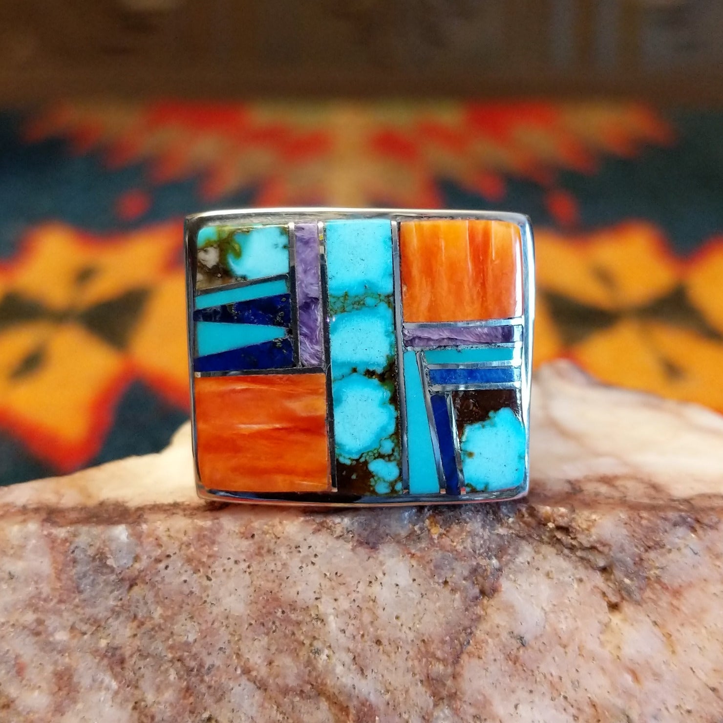Size 10.5 ring by Navajo artist B. Joe features hand-cut stones including bright turquoise with natural matrix, orange spiney oyster shell, deep blue lapis, and elegant charoite (purple).  Front view