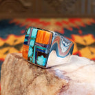 Size 10.5 ring by Navajo artist B. Joe features hand-cut stones including bright turquoise with natural matrix, orange spiney oyster shell, deep blue lapis, and elegant charoite (purple).  Side view