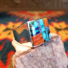 Size 10.5 ring by Navajo artist B. Joe features hand-cut stones including bright turquoise with natural matrix, orange spiney oyster shell, deep blue lapis, and elegant charoite (purple).  Side view