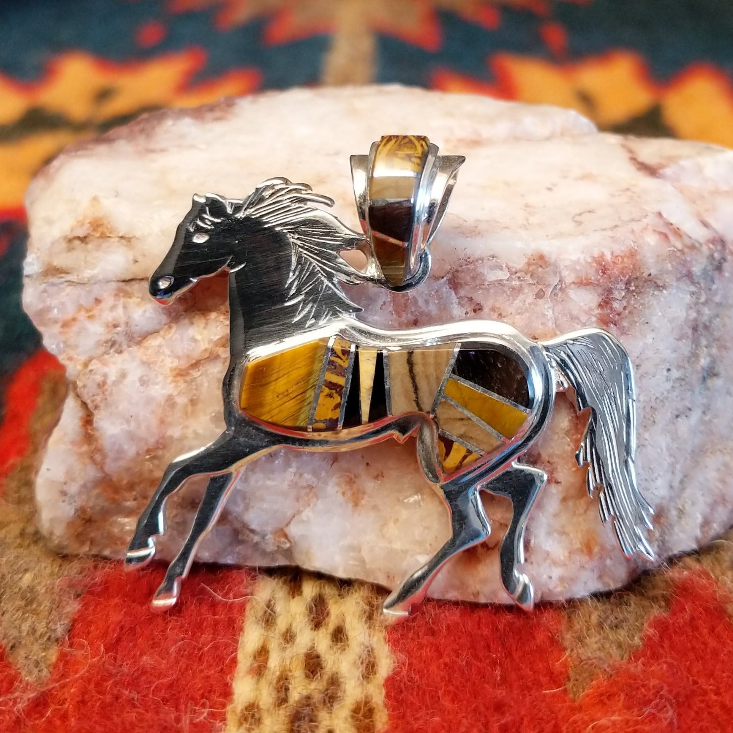 Navajo horse pendant handcrafted in sterling silver and showcases a dynamic inlay of Tiger’s Eye, Black Onyx, and Picture Jasper.  Front view