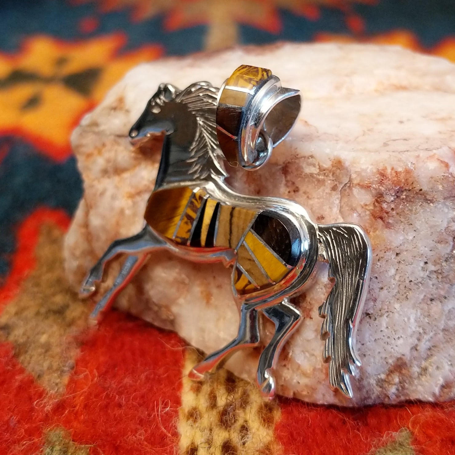 Navajo horse pendant handcrafted in sterling silver and showcases a dynamic inlay of Tiger’s Eye, Black Onyx, and Picture Jasper. Side view