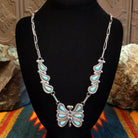 Butterfly-shaped necklace with turquoise stones on a black necklace bust.