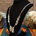 Butterfly necklace on a black mannequin bust, side view.