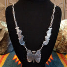 Back view of butterfly necklace on a black stand.