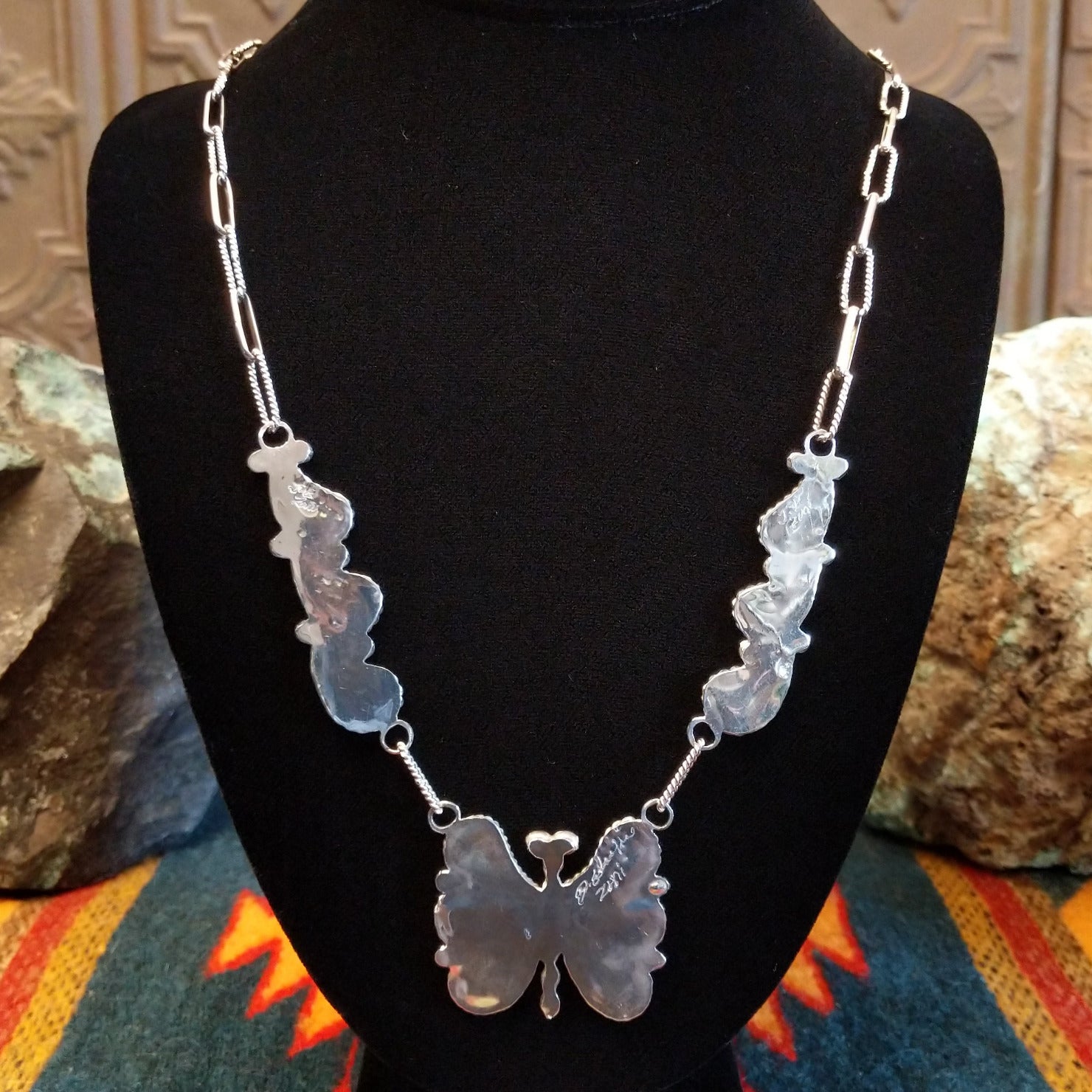 Back view of butterfly necklace on a black stand.
