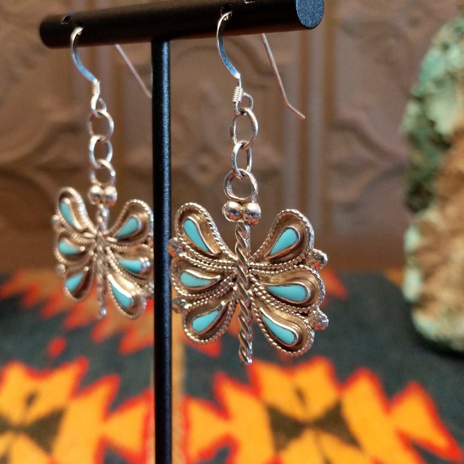Butterfly-shaped earrings with turquoise on a stand, side view.