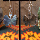 Butterfly-shaped earrings with turquoise on a stand, back view.