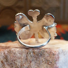 Butterfly-shaped silver and turquoise ring on a rock display, back side view.