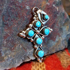 Sterling silver cross pendant with snake eye turquoise stones by Zuni artisan L.B. , showing bale in different position