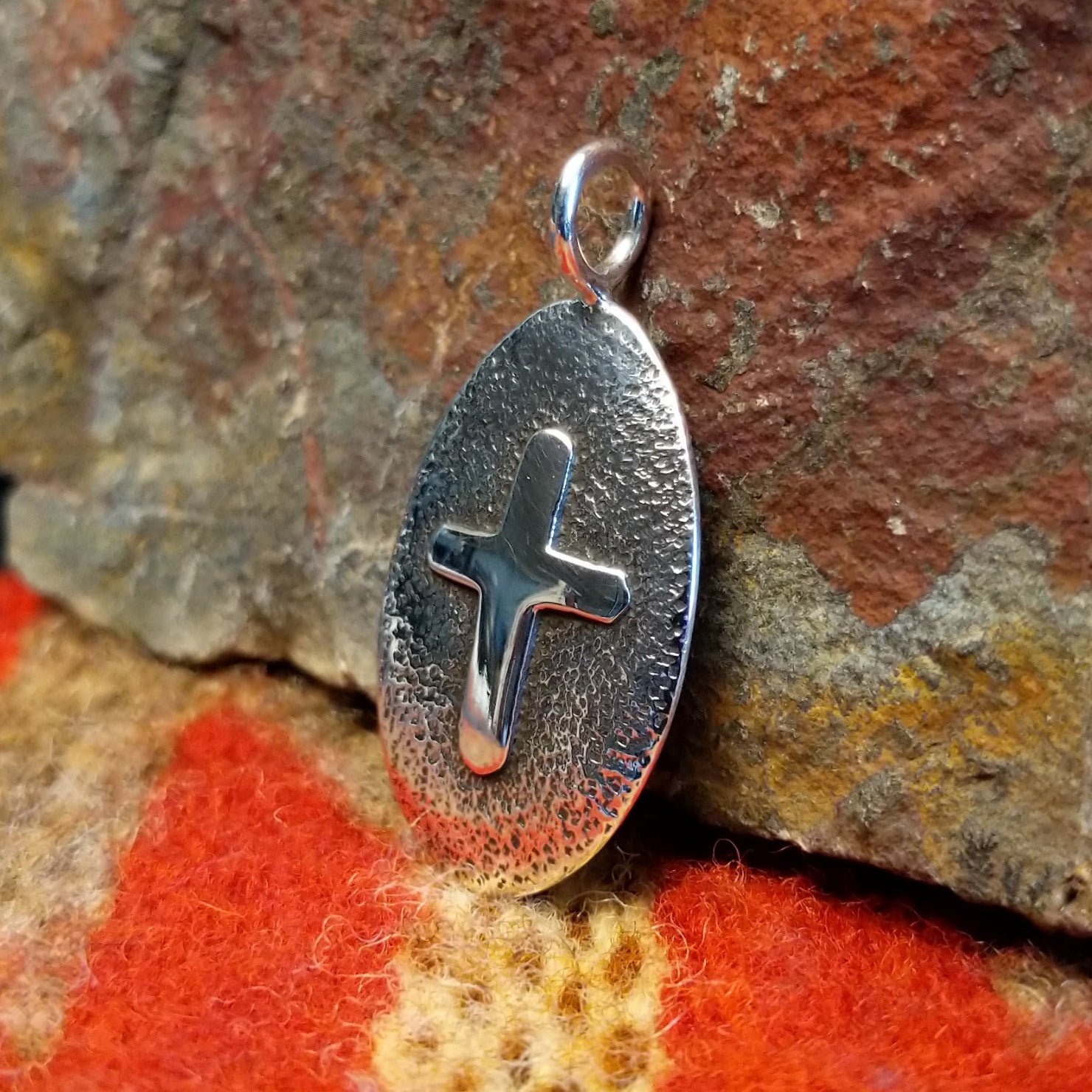 Oval sterling silver pendant with central cross by Navajo artisan Raymond Coriz.