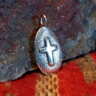 Oval sterling silver pendant with central cross by Navajo artisan Raymond Coriz.