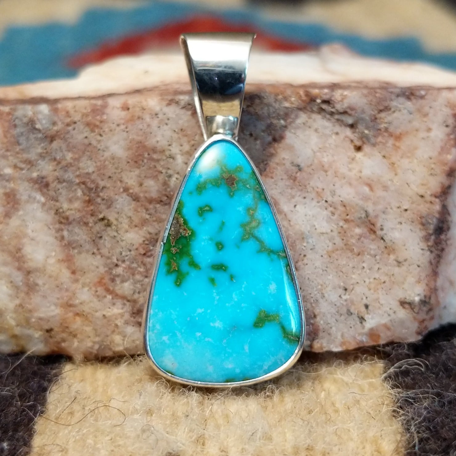 Teardrop sterling silver pendant featuring a polished Sonoran Gold turquoise stone with vivid blue-green color and natural golden matrix, handcrafted by Bernyse Chavez.  Front view.