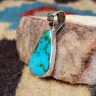Teardrop sterling silver pendant featuring a polished Sonoran Gold turquoise stone with vivid blue-green color and natural golden matrix, handcrafted by Bernyse Chavez.  Side view.