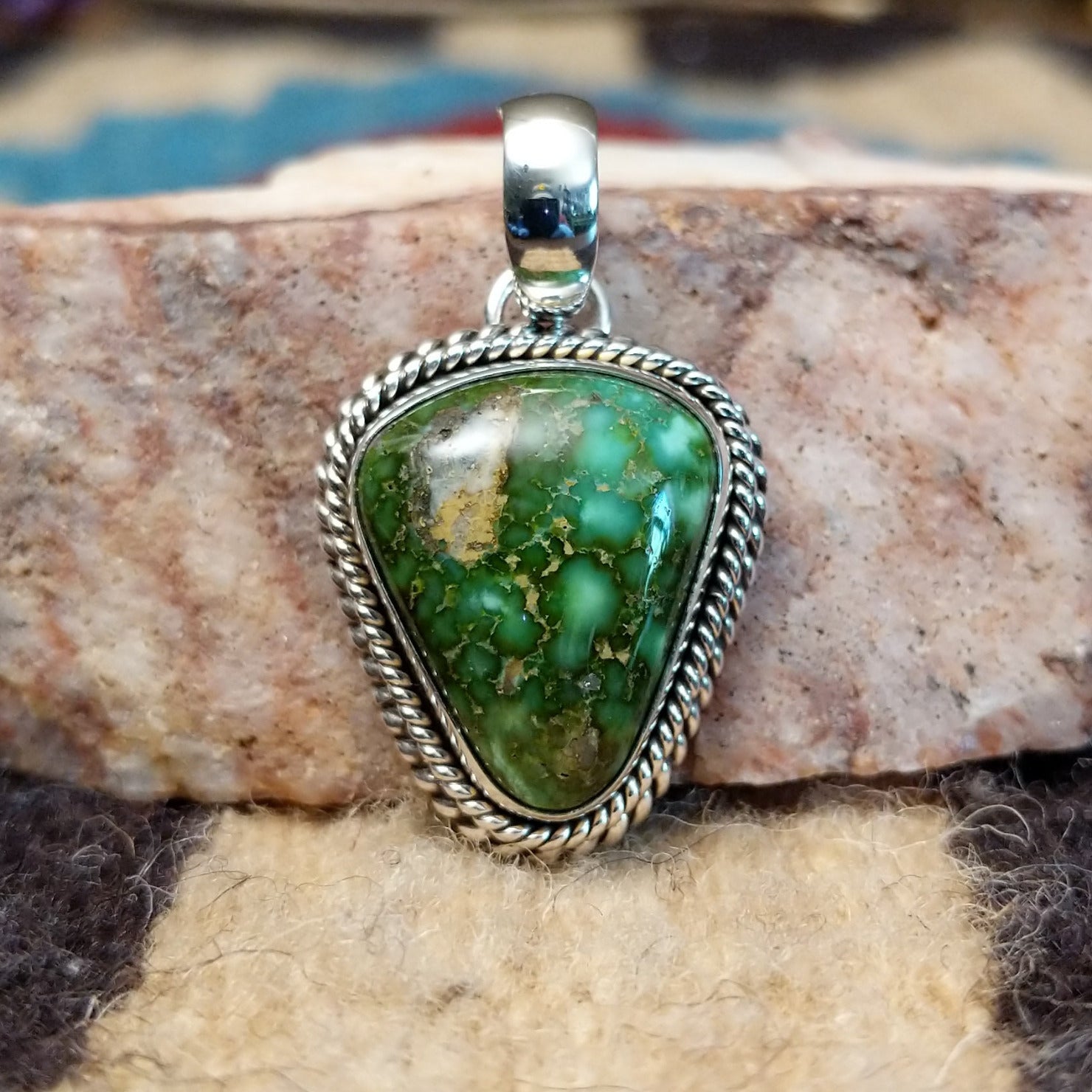 Triangular sterling silver pendant featuring a polished Sonoran Gold turquoise stone with blue-green tones and natural golden matrix, handcrafted by Navajo artist Artie Yellowhorse.  Front view.