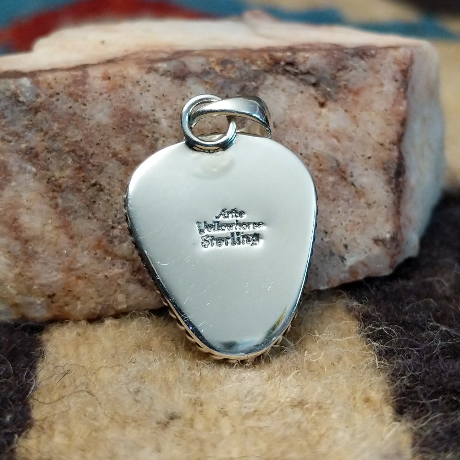 Triangular sterling silver pendant featuring a polished Sonoran Gold turquoise stone with blue-green tones and natural golden matrix, handcrafted by Navajo artist Artie Yellowhorse.  Back view with artisan and silver stamp.
