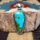 Deltoid-shaped sterling silver pendant featuring Sonoran Gold turquoise with vivid blue-green tones and natural golden matrix, handcrafted by Navajo artist Artie Yellowhorse.  Front view.